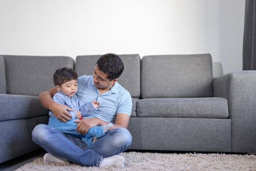 Mexican father and son playing on the carpet at home