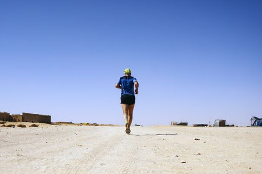 An athletic person running in a desert on a sunny day