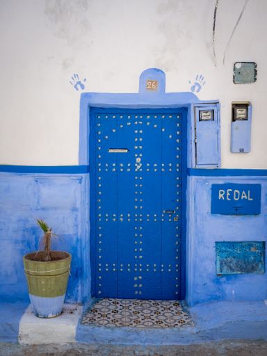 Traditional Moroccan style design of an ancient wooden entry door. In the old Medina. Typical, old, blue intricately carved, studded, Moroccan riad d