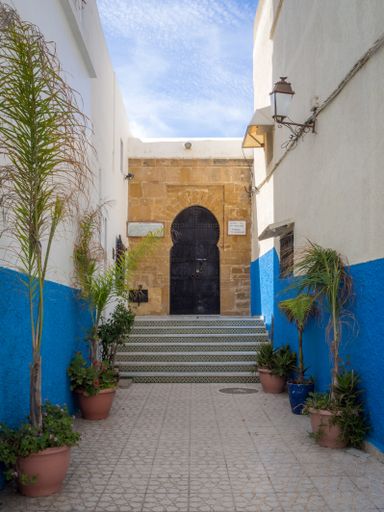 Traditional Moroccan style design of an ancient wooden entry door. In the old Medina. Typical, old, blue intricately carved, studded, Moroccan riad d
