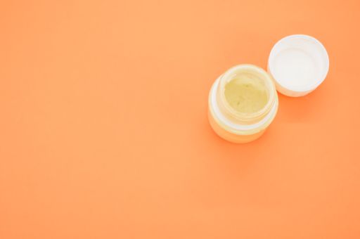 A top view of a small opened can of white gouache paint isolated on a coral background