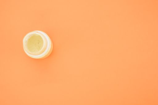A top view of a small opened can of white gouache paint isolated on a coral background