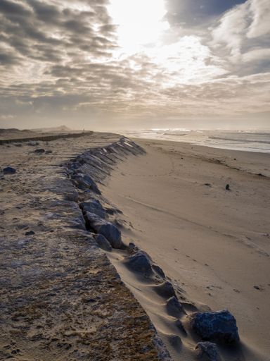 A vertical high angle shot of the sandy ground under the cloudy sky