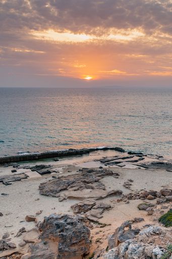 Vertical shot ofbeautiful cloudy sunset in cala delta on the island of Mallorca, Spain.