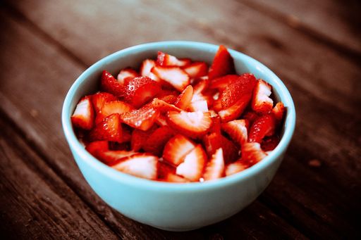 A selective focus shot of fresh strawberries in a bowl on a wooden table