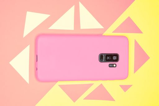 A top view of a pink smartphone on a yellow and pastel pink surface with colorful triangles on it