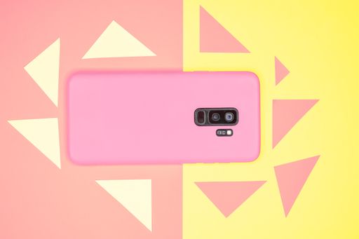 A top view of pink mobile phone case isolated on pink and yellow background with copy space