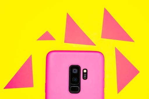 A top view of pink mobile phone case isolated on pink and yellow background with copy space