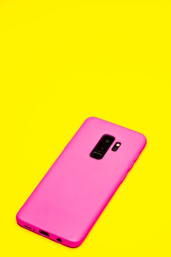 A pink phone on the pink and yellow background with paper triangles