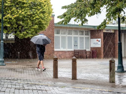 A closeup of a  person  walking down a city street in the pouring rain