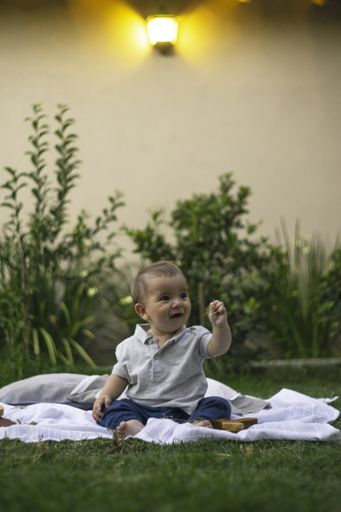 A vertical shot of a cute baby sitting on a cloth outdoors