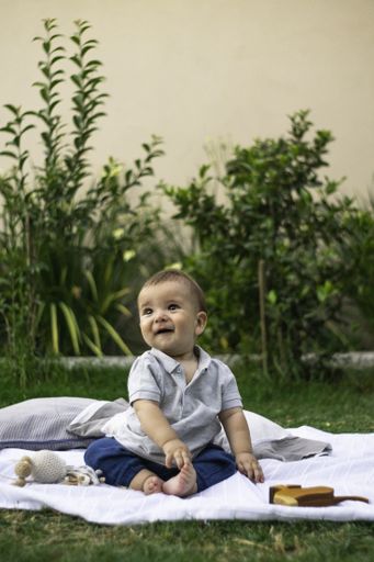A vertical shot of a cute baby sitting on a cloth outdoors