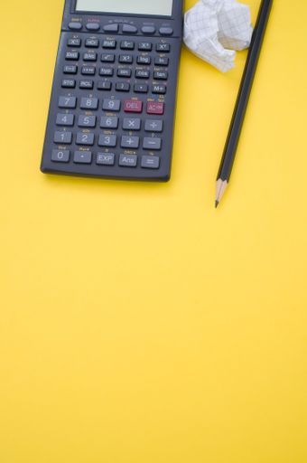 A vertical shot of a scientific calculator, pencil, grid notepad and a crumpled paper isolated on a yellow background with space for your text