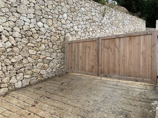 The closed wooden gates near a stone wall