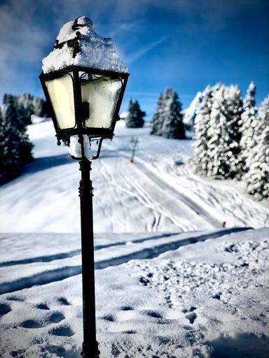 This beautiful snow-covered street lamp is perched atop a snowy mountain, providing a charming and festive glow in the night