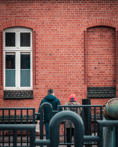 A back view of two builders looking at the brick wall of a building