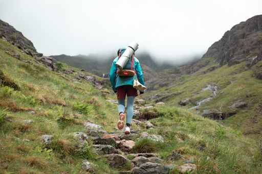 This woman is hiking up a steep hill with a backpack on her back