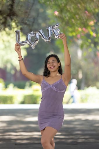 A young female outdoors in an open space, holding a sign with the word "Love"