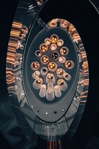 A vertical low angle shot of multiple illuminated chandeliers hanging from the Burj Khalifa ceiling