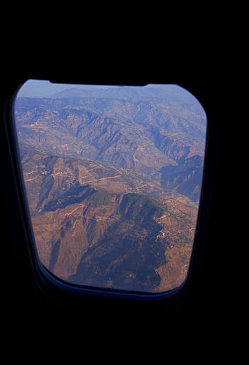 Aerial view of mountain range seen through an airplane window during sunset