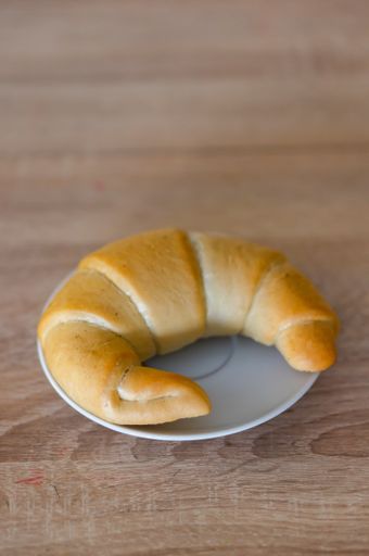 A vertical shot of a croissant on a small white plate