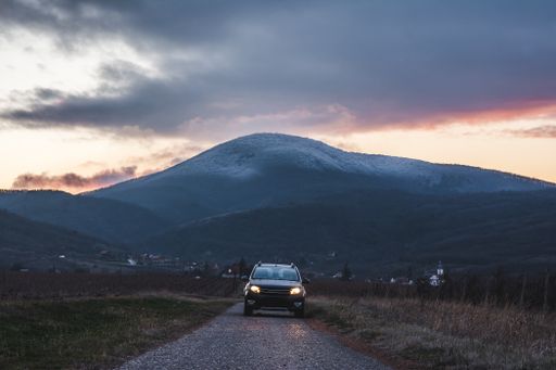 A car on the road with a mountain during the sunset