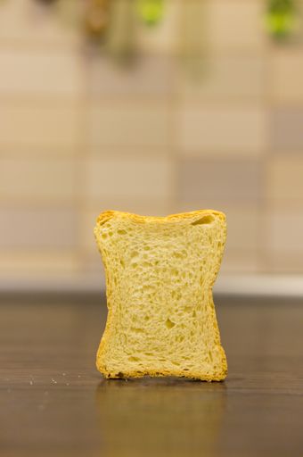 A vertical shot of a slice of toast on a wooden surface