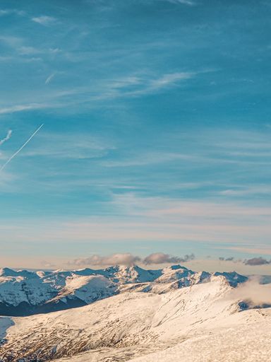 An aerial view of snow covered mountain landscape during sunset