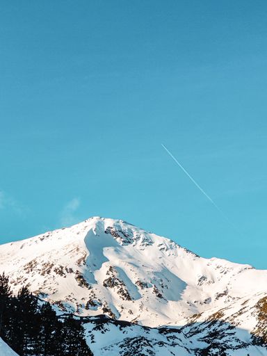 An aerial view of snow covered mountain landscape during sunset
