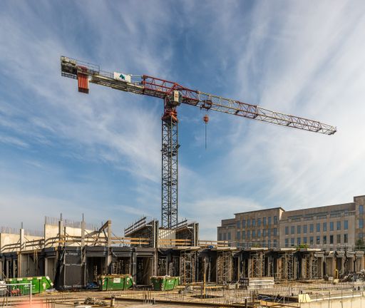 A scenic view of a building site with a large crane under a cloudy blue sky in the Netherlands