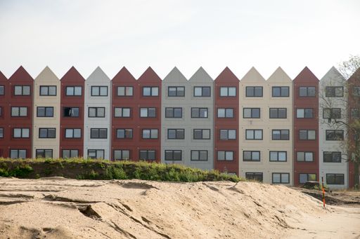 A low angle shot of a building with red and white sections and triangular roofs