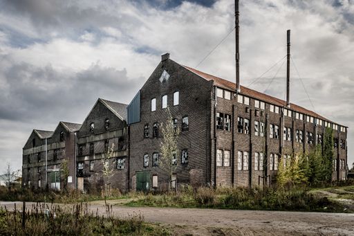 An old abandoned stone building with broken windows under the dark cloudy sky