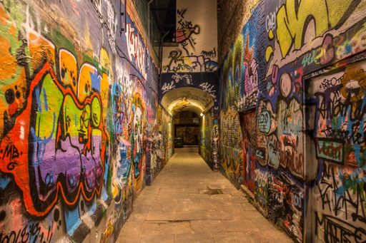 An arch in a narrow street with colorful graffiti all over the walls