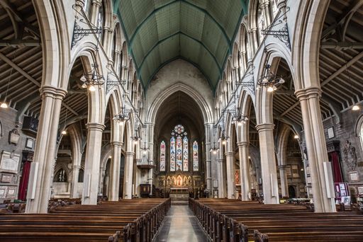 An inside view of a church with religious icons on the windows and stone arches