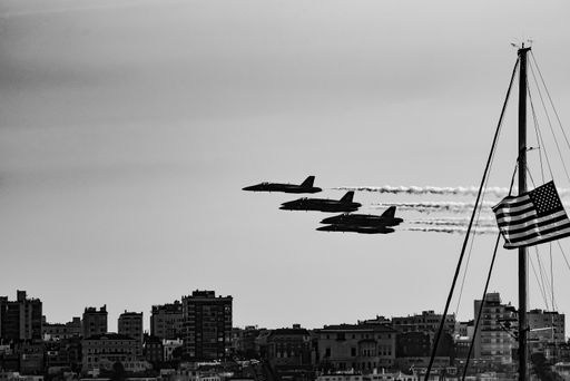 A grayscale shot of fighter jets in the sky with the American flag on the side