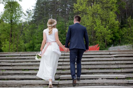 A shallow focus of a newly married couple holding hands and climbing up the stairs in a pa