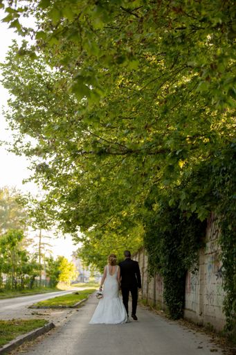 A shallow focus of a newly married couple holding hands and walking in a park
