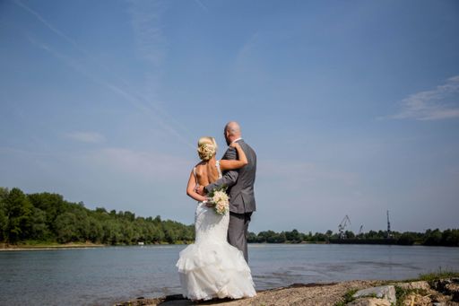 A shallow focus of a newly married couple standing near a river under a blue sky