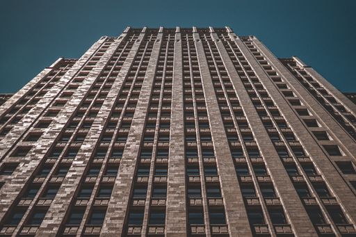 A low angle shot of a tall business building with a dark blue background