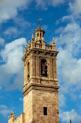 A vertical shot of a bell tower under a blue cloudy sky