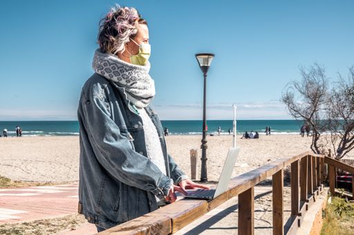 A closeup shot of a Spanish woman with her laptop at the beach on a sunny day