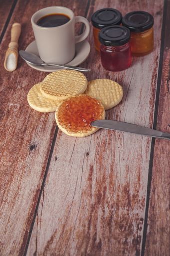 A table with two crackers with honey and jam