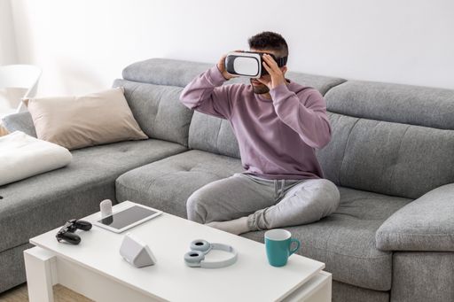 An adult male playing video games with a VR headset while sitting on the sofa