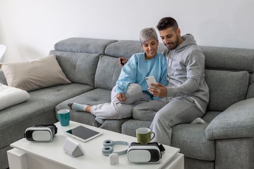 A young happy couple cuddling on a sofa and watching a video on a phone