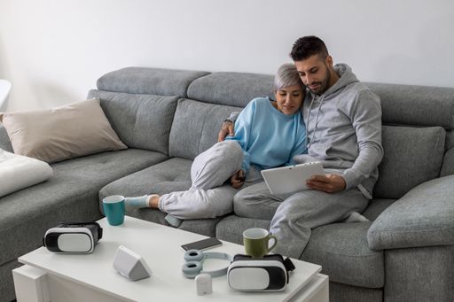 A young lovely couple cuddling on a sofa and watching a video on a tablet