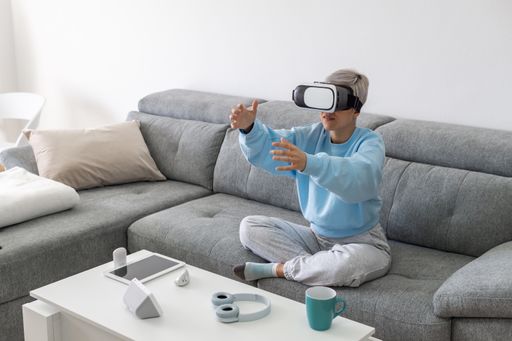 An adult woman playing video games with a VR headset while sitting on the sofa