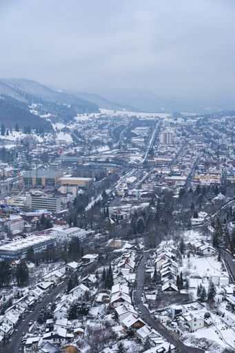 A vertical aerial shot of a city surrounded by hills captured on a cold, snowy day