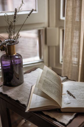 A vertical shot of an open old book on the table near the window