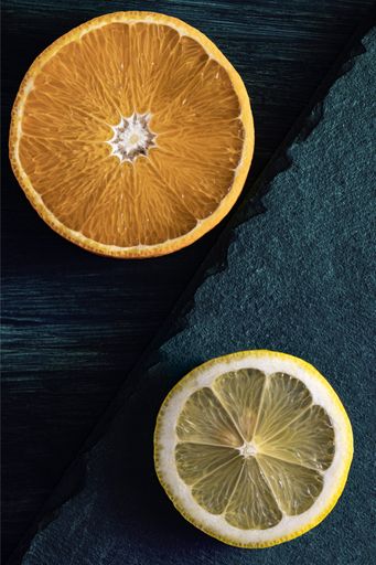 Orange and lemon slices on dark teal wood and stone background decoration.