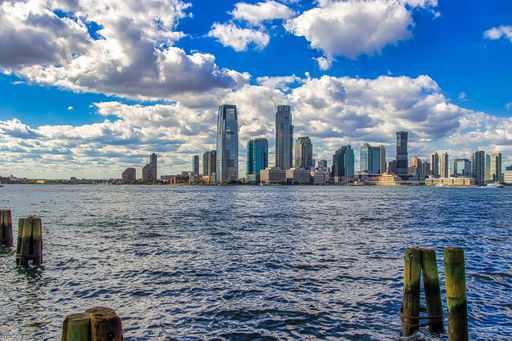 A majestic dramatic cloudscape over waterfront New York City skyline with modern high-rise buildings at daytime